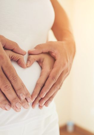 Pregnant Woman and Her Husband hand showing heart shape.
